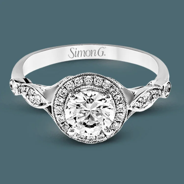 This sparkling white gold vintage inspired engagement ring features an exquisite halo and is set with .25 ctw round cut white diamonds.