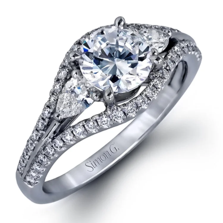 This 18K bridal set features a 3-stone engagement ring that takes a RD center with 2 pear shaped diamond sides 0.32 ctw, a split shank, and is outlined by round white diamonds 0.40 ctw. with Matching diamond band 0.14 ctw