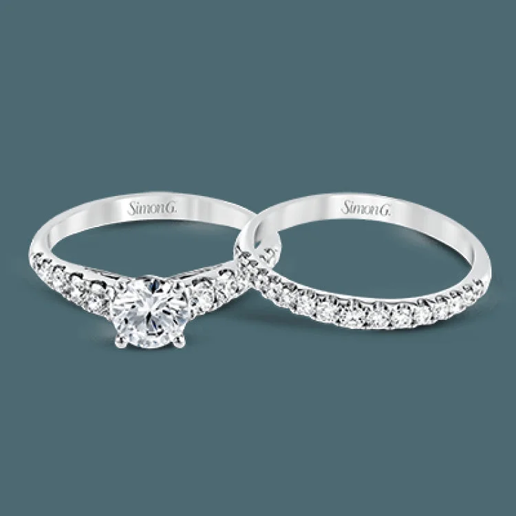 Elevating a classic design with modern elements, this exquisite white gold engagement ring and band are emphasized by .77 ctw of sparkling round cut white diamonds.