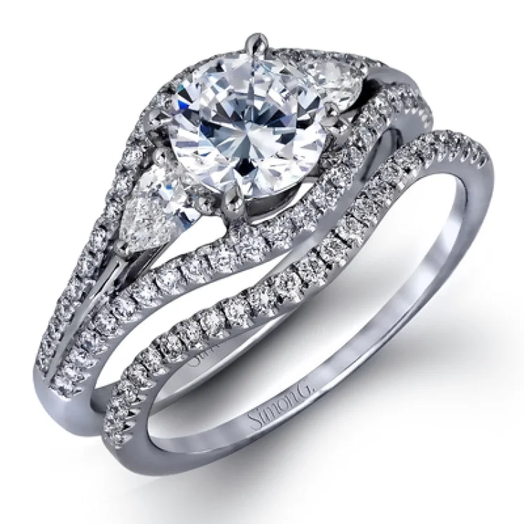 This 18K bridal set features a 3-stone engagement ring that takes a RD center with 2 pear shaped diamond sides 0.32 ctw, a split shank, and is outlined by round white diamonds 0.40 ctw. with Matching diamond band 0.14 ctw